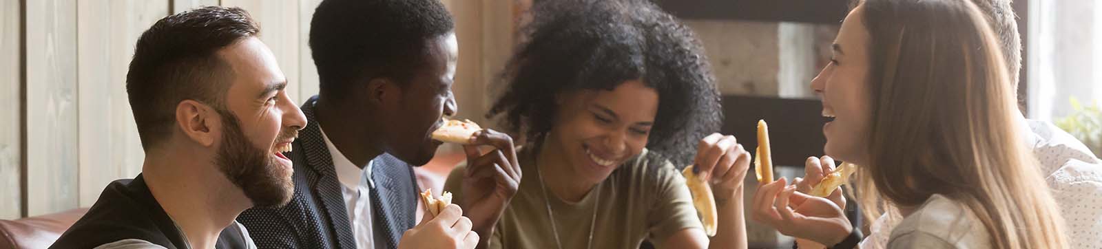 young adults sharing a pizza and laughing