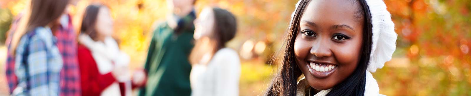 bright smiling young adult woman with friends in background