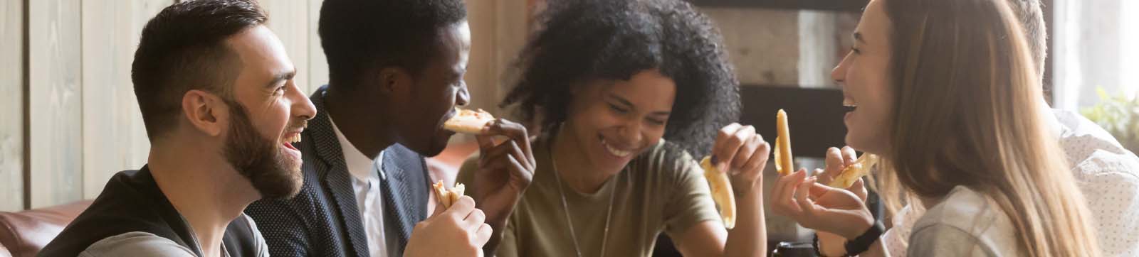 group of young adults with varying ethniciity sharing pizza